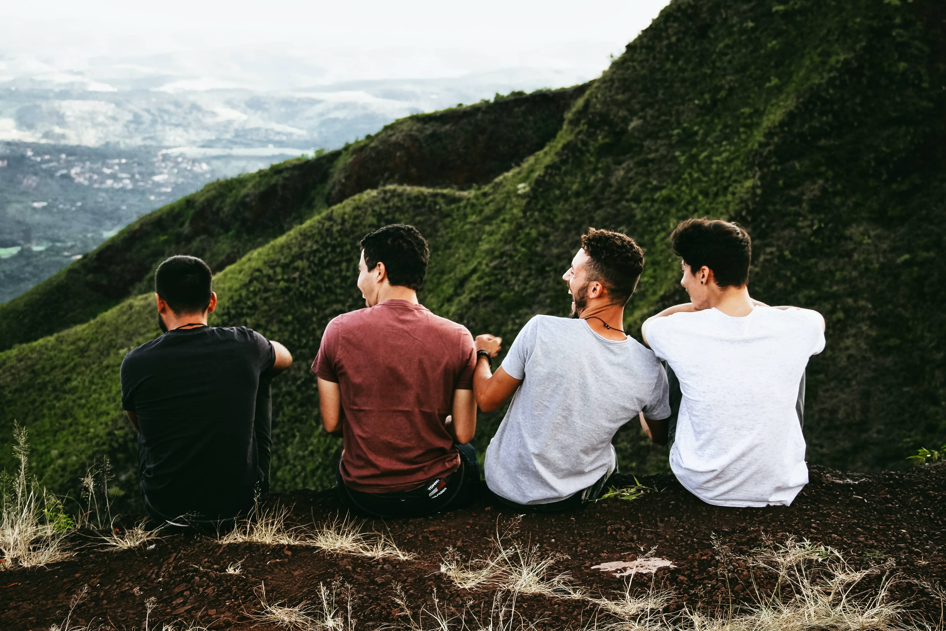 Four students sitting together on a hillside above a valley.